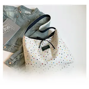 Close-up of bohemian canvas tote bag featuring colorful polka dots and a black ribbon bow