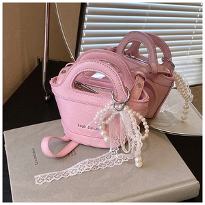 Detailed view of pink leather mini handbags featuring pearl beads and lace bows on a book