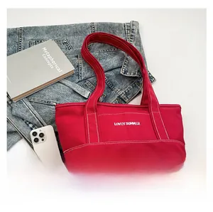 Close-up of red canvas tote bag with Lovey Summer text and contrast white stitching details