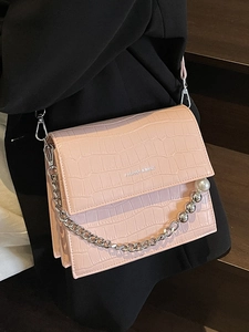 Pink stone pattern crossbody bag with pearl chain and silver strap shown on a black suit