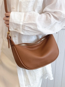Minimalist brown pebbled leather crescent tote bag for women shown as shoulder carry