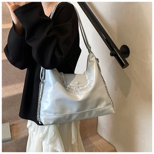 Détail du sac cabas en similicuir argenté avec bordure en dentelle blanche et chaîne en métal