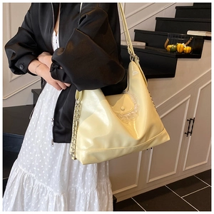 Détail macro du sac cabas en cuir crème avec bordure en dentelle et bandoulière chaîne