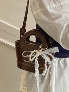 Brown leather mini handbag with pearl lace bow charm and crossbody shoulder strap