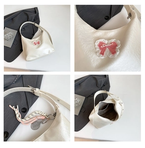 Detail view of ivory tote bag with pink lace bow, tennis racket charm and inner pocket