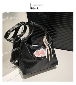 Detail of black vintage oily leather tote bag with a pink lace bow and woven charm