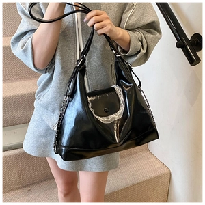 Détail du sac fourre-tout en cuir brillant noir avec dentelle et chaîne argentée