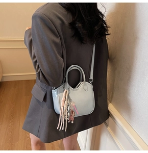 Detalle de bolso de cuero azul claro con borde en U y colgante decorativo Love Life