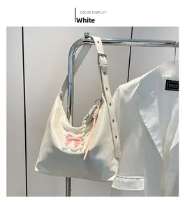 Detail of white PU leather tote bag featuring a pink bow lace and woven tassel pendant