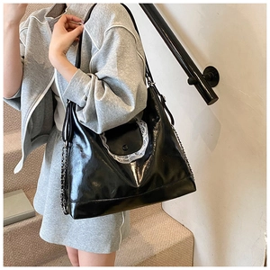 Détail du grand sac cabas noir brillant avec bordure en dentelle blanche porté par mannequin