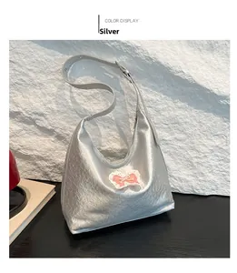 Detail of silver metallic leather hobo bag with pink bow lace patch on stone surface