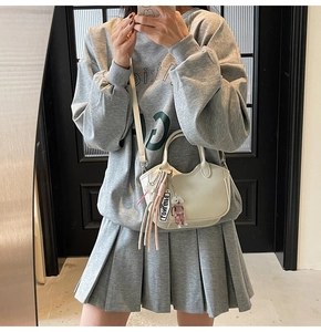Detalle del bolso de media luna blanco crema con colgante de perrito y borlas largas