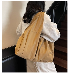 Detail of khaki nylon tote bag with pleated texture and side pockets on shoulder