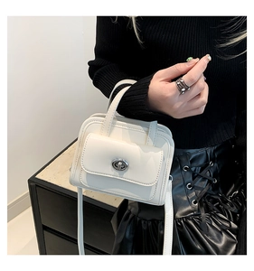 Dettaglio di una mini borsa in pelle bianca con chiusura a scatto argento e tracolla