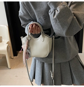Detalle del bolso de cuero blanco crema con un tierno colgante de perrito y correa