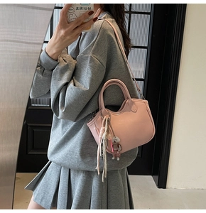 Bolso rosa con colgante de oso y borlas mostrado en un elegante selfie de espejo