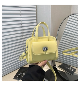 Dettaglio ravvicinato di una mini borsa gialla con chiusura a scatto in metallo e manico