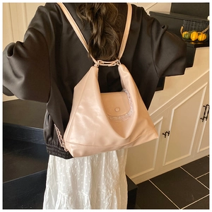 Détail d'un sac à dos rose en cuir souple avec dentelle blanche porté par un modèle