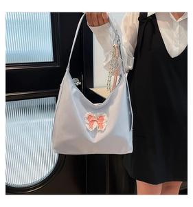 Detail of light blue tote bag featuring lace circular patch and pink ribbon bow decoration