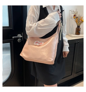 Close-up of pink leather tote bag featuring elegant lace bow and braided side detail