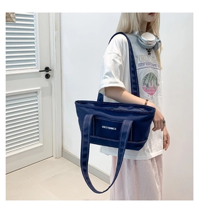 Detail view of navy blue canvas tote bag showing white LOVEY SUMMER print and contrast stitching
