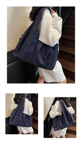 Detail of a large navy blue tote bag with ruched texture shown on a white outfit