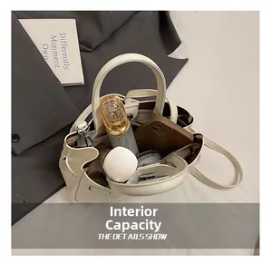 Detailweergave van de ruime interne capaciteit van de beige bucket bag met litchi-patroon