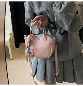 Bolso tipo cubo rosa de cuero PU con colgante de conejo y borla llevado por modelo