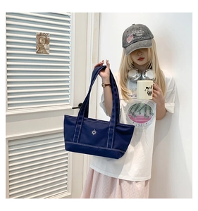 Detailed view of the dark blue canvas tote bag with white star logo and contrast stitching