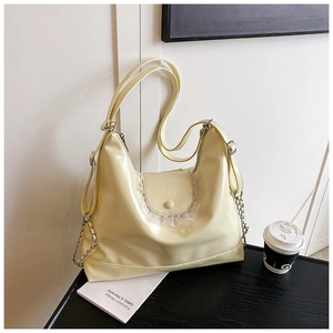 Détail d'un sac cabas en cuir souple jaune pâle avec bordure dentelle et chaîne métal
