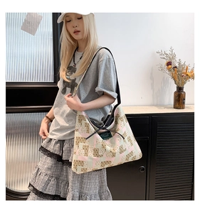 Detail view of large canvas tote bag with pink and green checkered pattern and black strap