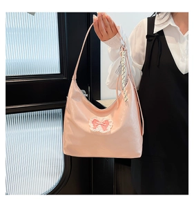Pink minimalist hobo tote bag featuring pink and white embroidered bow with a woven charm
