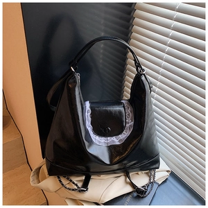 Détail du sac cabas en similicuir noir avec bordure en dentelle blanche et bandoulière chaîne