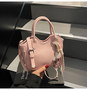 Bolso rosa de cuero PU con bordes ondulados, hebillas plateadas y un llavero de oso
