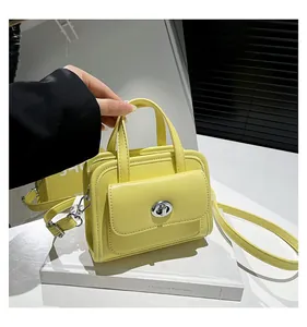 Dettaglio della borsa in pelle gialla con chiusura rotante in metallo argentato e manico