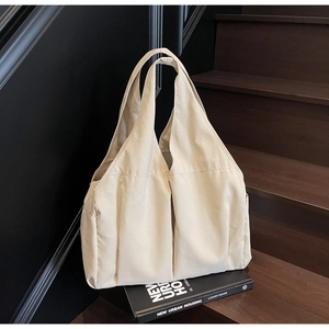 Detailed texture of a beige large-capacity fabric hobo tote bag on dark wooden stairs