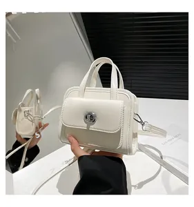 Dettaglio di una mini borsa a cartella bianco crema con chiusura girevole argento e finitura opaca
