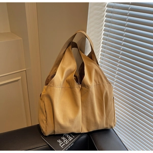 Detailed view of khaki canvas tote bag on black leather sofa showing textured fabric