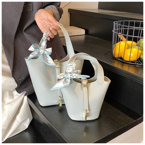 Detailansicht grauer Leder-Beuteltaschen mit Seidenschal-Dekor und goldenem Vorhängeschloss