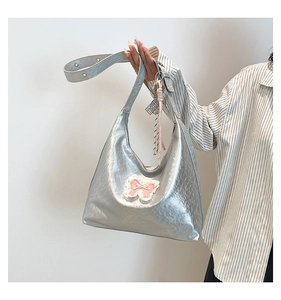 Detail of silver metallic crescent hobo bag with pink bow accent and ribbon charm