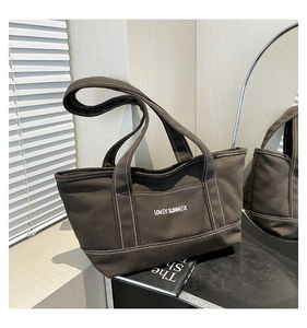 Close-up of dark brown canvas tote bag with Lovey Summer text and white stitching details