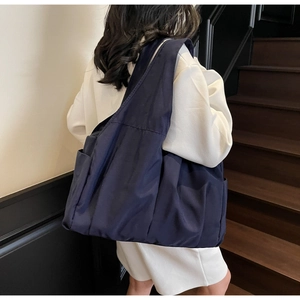 Detail view of navy blue quilted nylon tote bag with wide strap and side pocket