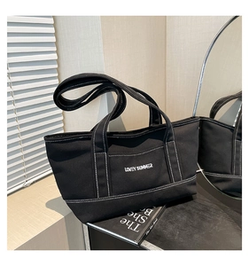 Detail of black canvas tote bag with white contrast stitching and Lovey Summer embroidery