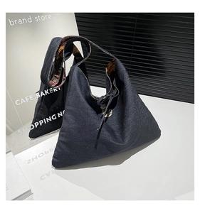 Detail of blue denim triangle tote featuring logo printed lining and drawstring closure