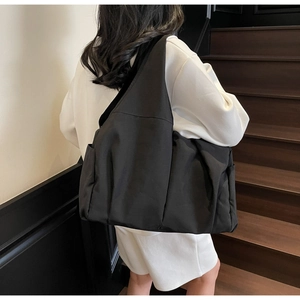 Minimalist large black nylon tote bag showing spacious capacity and hidden side pocket