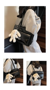 Detail of black vintage messenger bag with metal buckle and cute white rabbit keychain