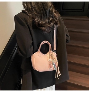 Detalle de bolso de mano rosa media luna con colgante de oso y correa con logo