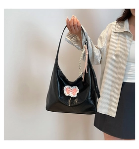 Close-up of black tote bag featuring lace trim, pink bow detail, and striped charm