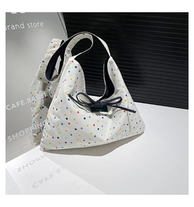 Close-up of white canvas tote with colorful polka dots and dark blue bow detail