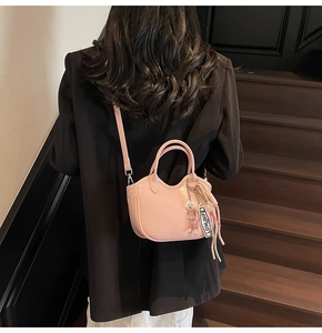 Bolso bombonera de cuero brillante rosa con colgante de oso blanco y etiqueta de logo